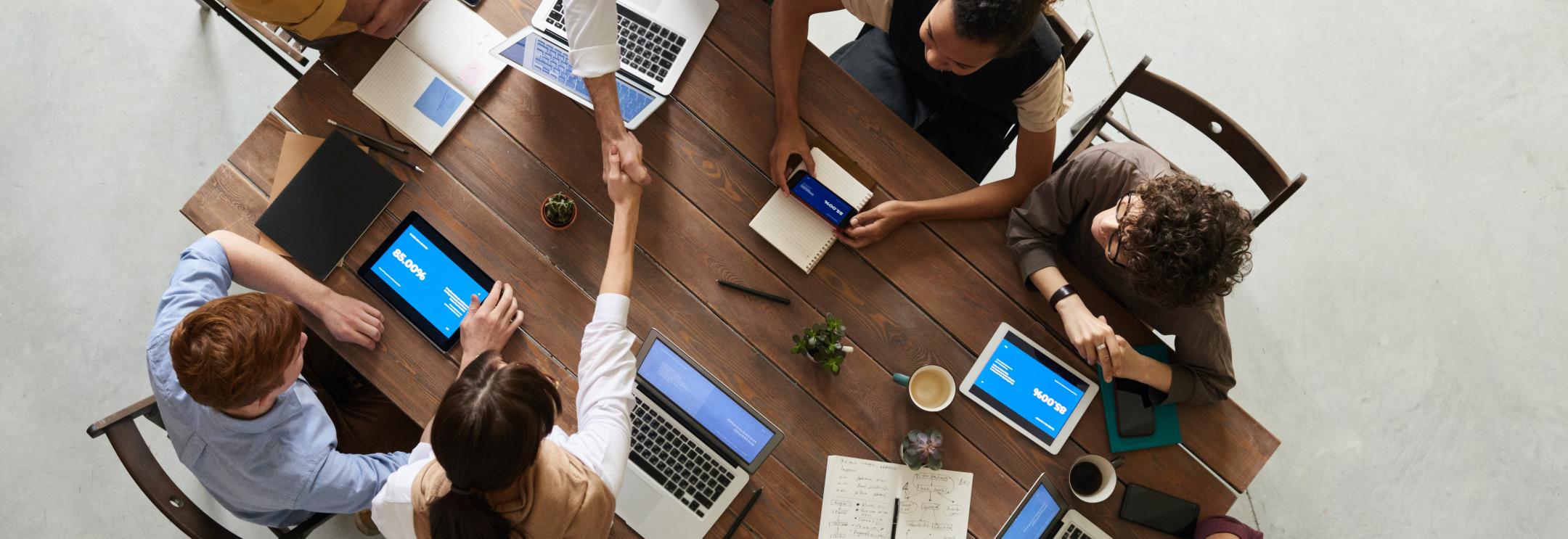 Employee shaking hand with a colleague around a table
