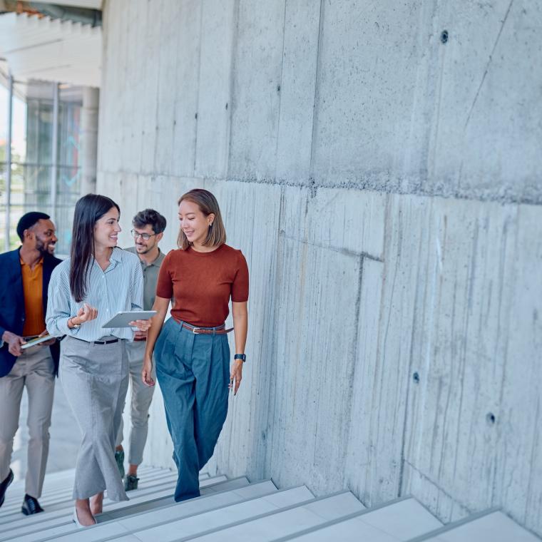 Group of business people walking up stairs in modern office building discussing work 