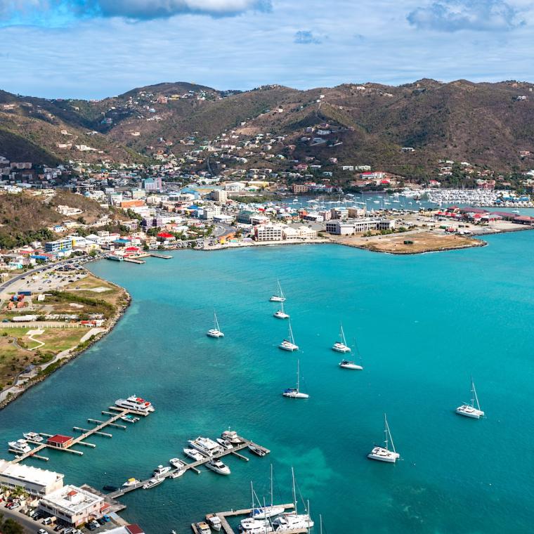 An aerial view showcases a vibrant harbor in the British Virgin Islands, where sailboats dot the turquoise sea