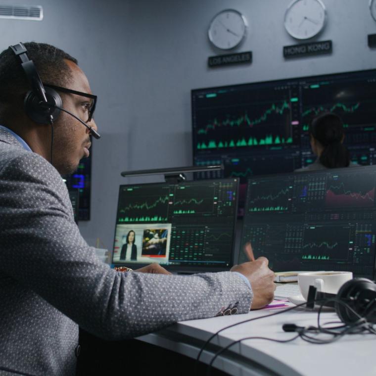 trader with pen in hand works at computer with displayed real-time stocks