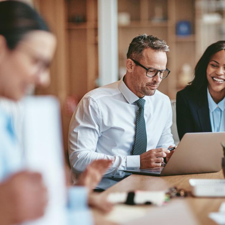 Two smiling diverse businesspeople using a laptop together at work