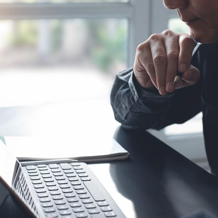 Pensive business man thinking while serious working on laptop computer from home office