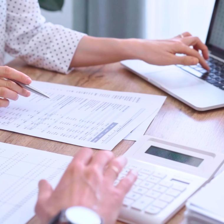 Professional female bookkeeper or auditor are working on business finances with a colleague, using calculator and laptop. Finance audit and taxes