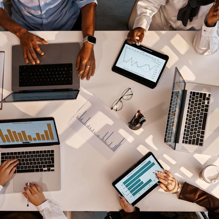 Team working with graphs and data on laptops and tablets at office table
