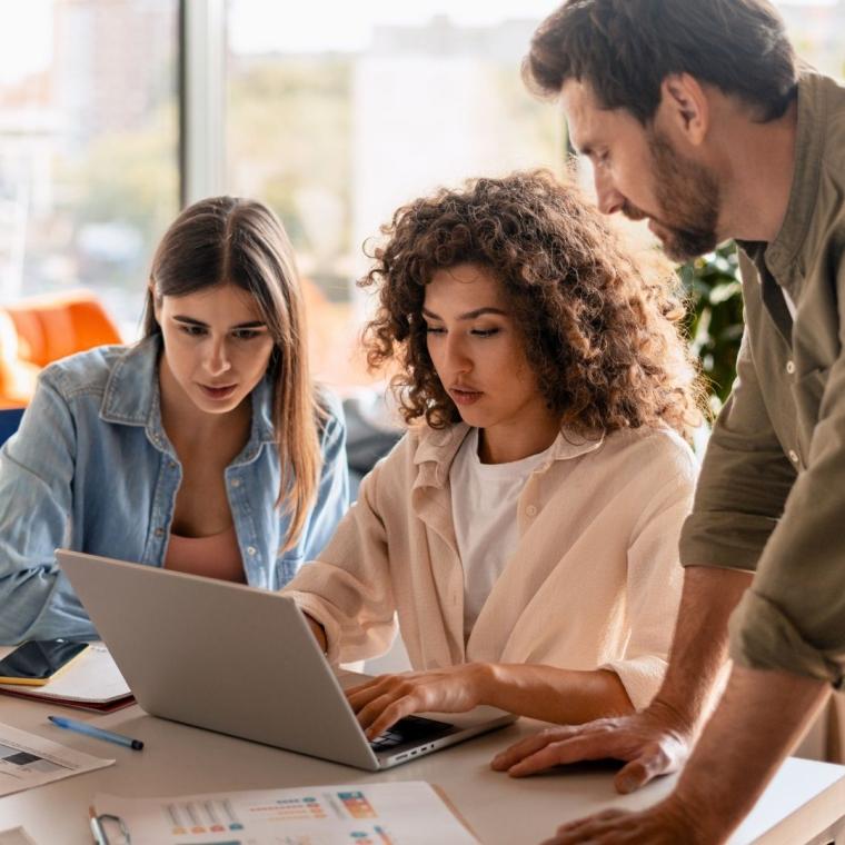 Marketing team analyzing data and collaborating on laptop in office meeting