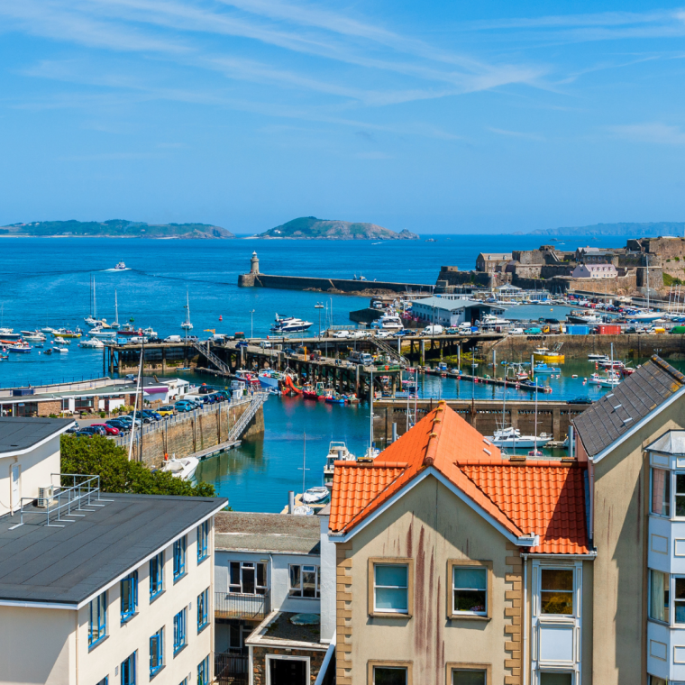 High angle view over Harbor of Saint Peter Port, Guernsey, Channel Islands, UK. The Islands of Herm and Sark are visible in the distance 
