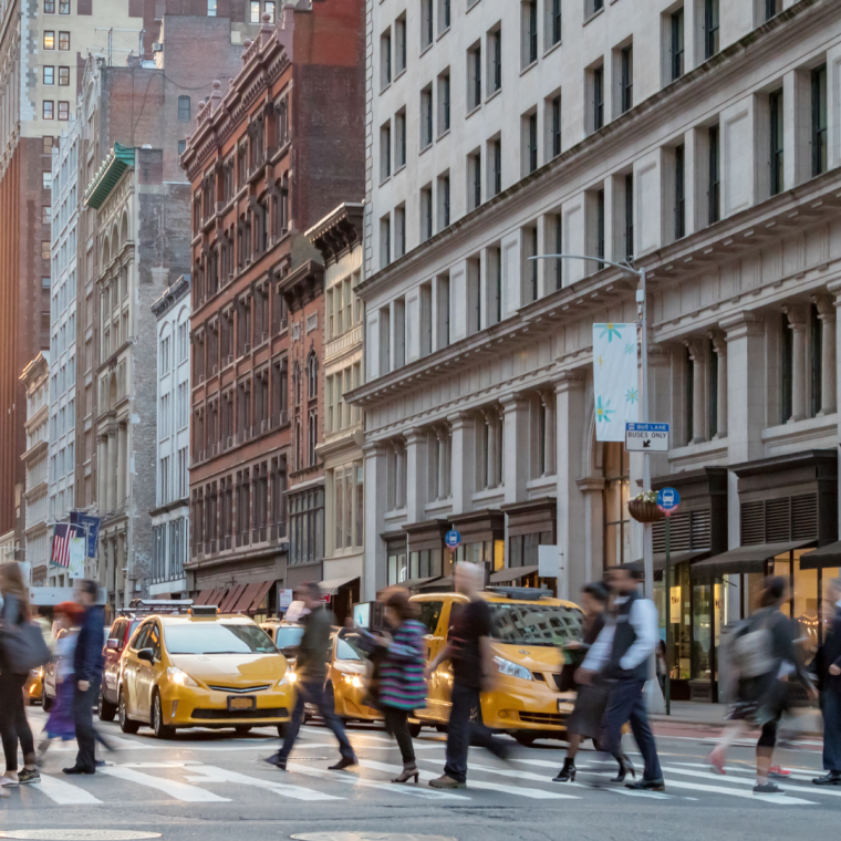 Fast paced street scene with people walking across a busy intersection on Broadway in Manhattan New York City 