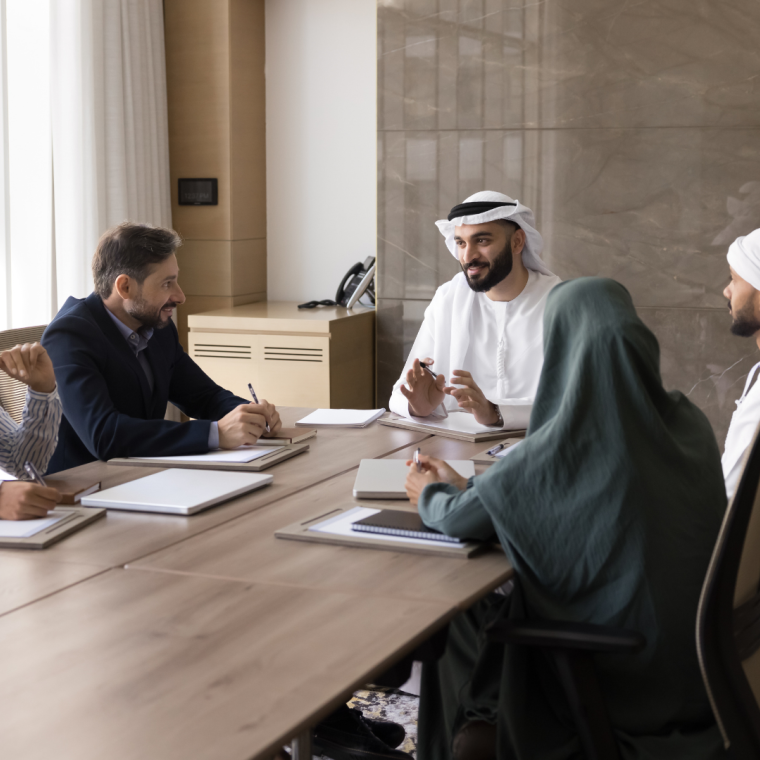 Happy young Arab business leader man talking to diverse partners at meeting. Multiethnic business team of Arabic and European colleagues discussing cooperation, teamwork.
