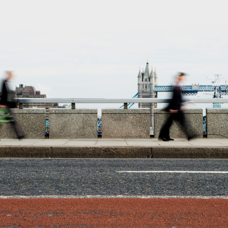London Rush Hour: Business commuters, blurred by motion, walking along London Bridge with Tower Bridge in the background.