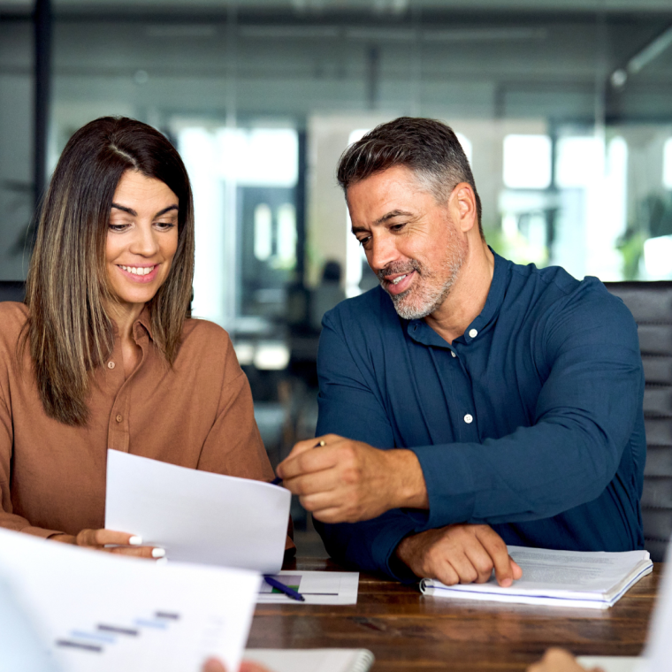 Professional executives business group working with documents at meeting in office. Smiling corporate board team having discussion planning company project strategy sitting at board room table.