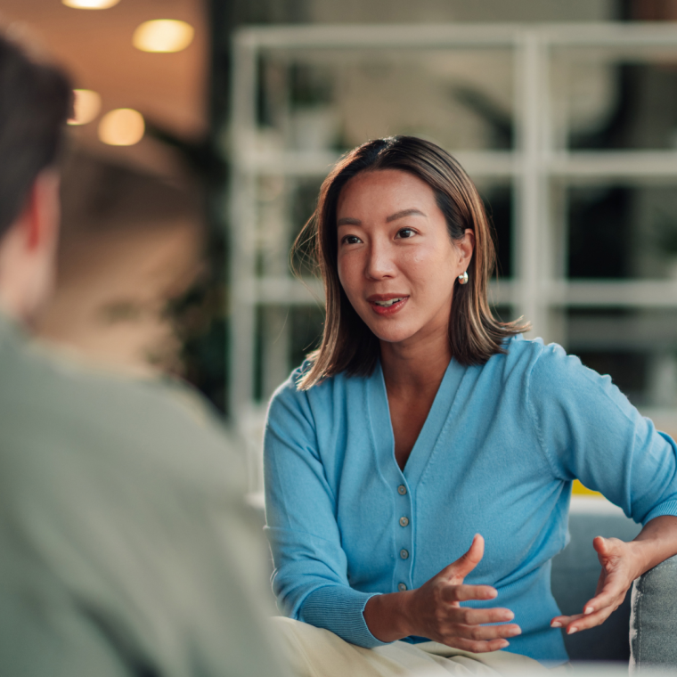 Asian businesswoman communicating with male colleague, discussing project, collaborating in modern office lounge 