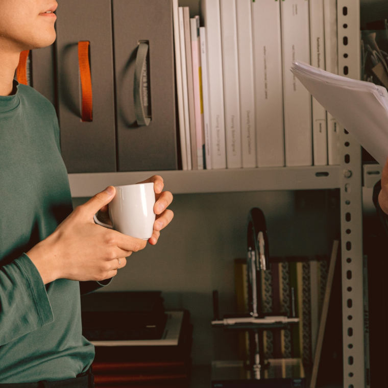 Two colleagues talking with a coffee in hand. 