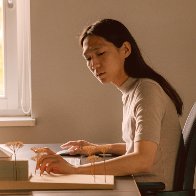 Asian woman working on a laptop, reviewing documents. 