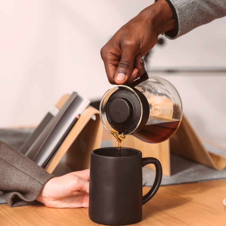 Business professional pouring coffee for colleague. 