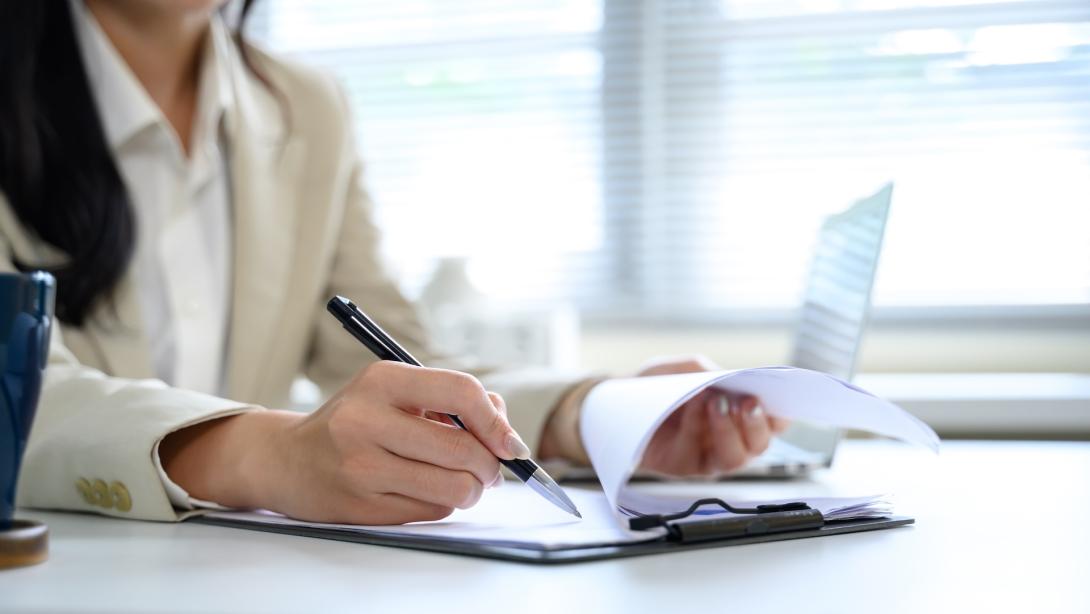 Close up of businesswoman hands writing notes on a clipboard during office work