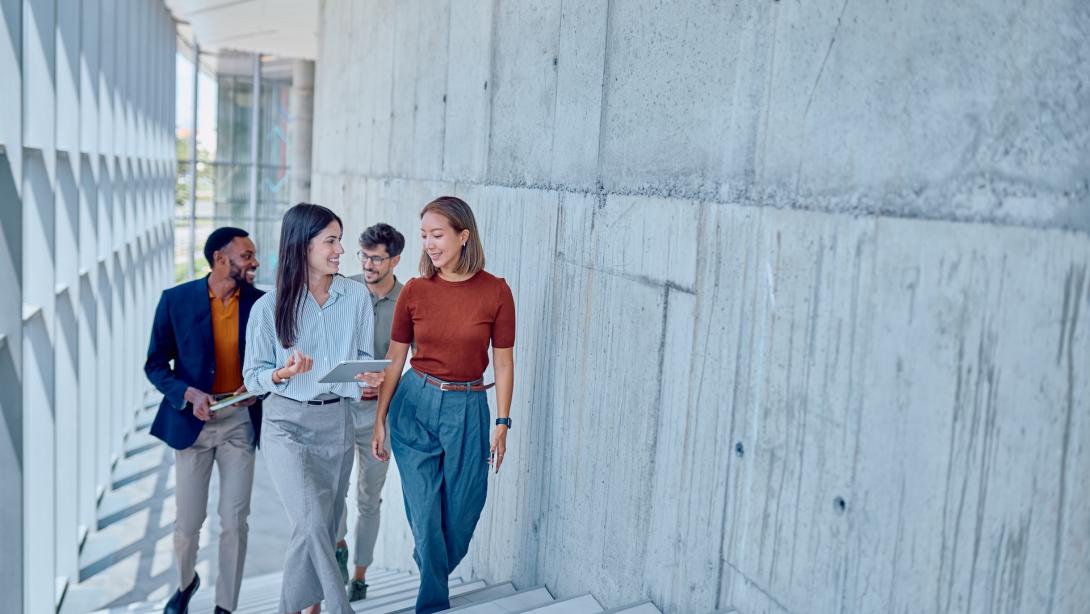Group of business people walking up stairs in modern office building discussing work