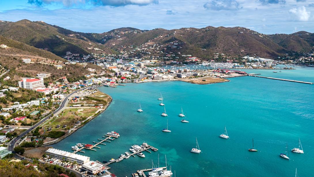 An aerial view showcases a vibrant harbor in the British Virgin Islands, where sailboats dot the turquoise sea
