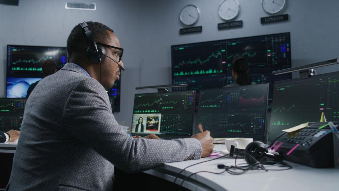 trader with pen in hand works at computer with displayed real-time stocks