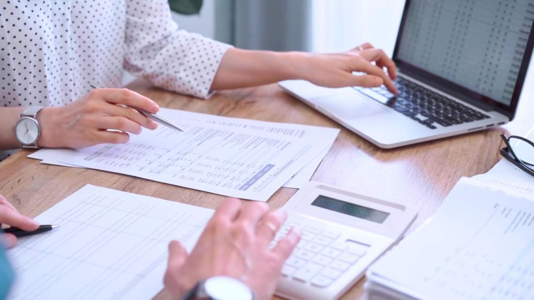 Professional female bookkeeper or auditor are working on business finances with a colleague, using calculator and laptop. Finance audit and taxes