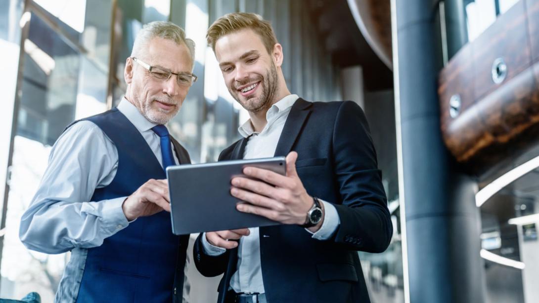 Professional young man showing more senior colleague work on an iPad