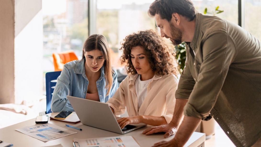 Marketing team analyzing data and collaborating on laptop in office meeting