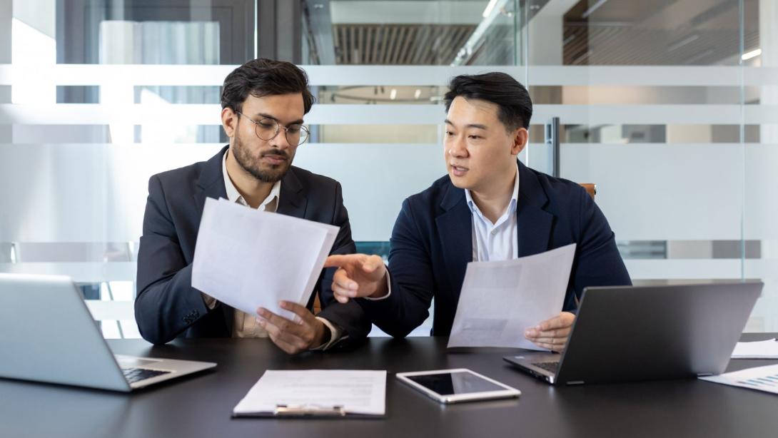 Asian businessmen analysing paperwork in corporate setting