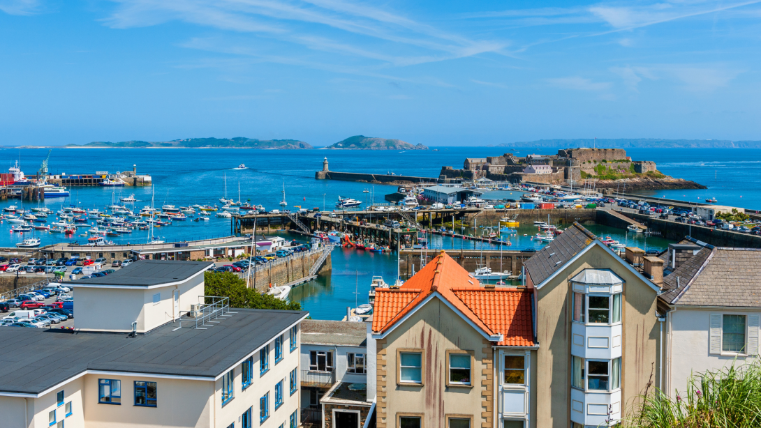 High angle view over Harbor of Saint Peter Port, Guernsey, Channel Islands, UK. The Islands of Herm and Sark are visible in the distance 