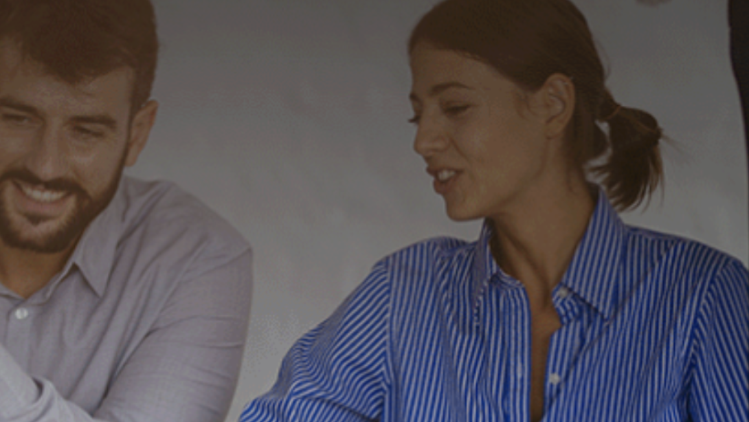 Three people in shirts talking over a laptop