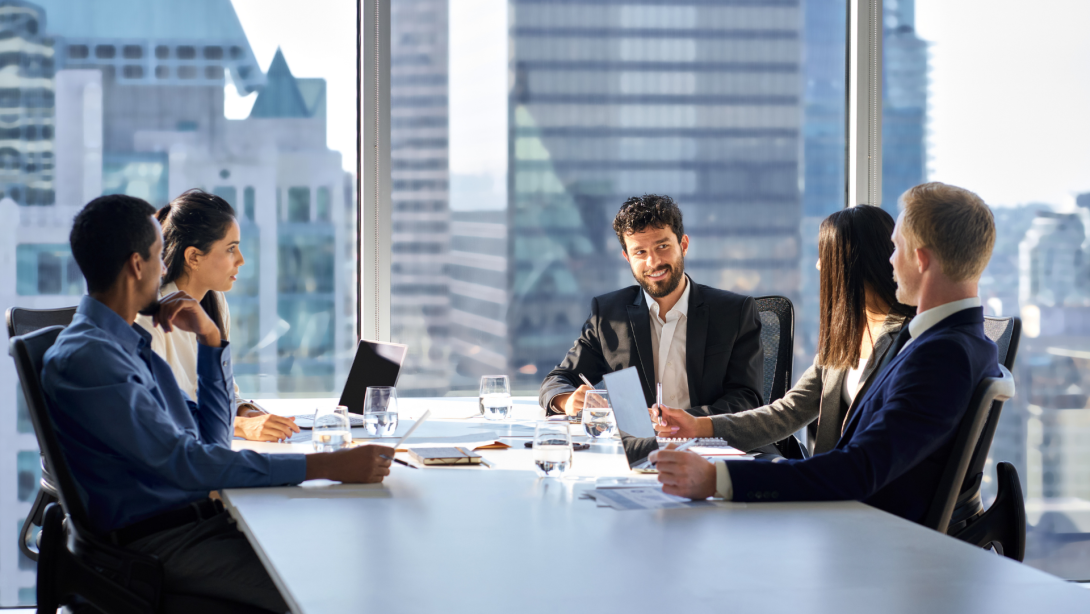 Happy international multiethnic professional business team, diverse executive colleagues people discussing financial project working together in office at group meeting table in corporate board room.