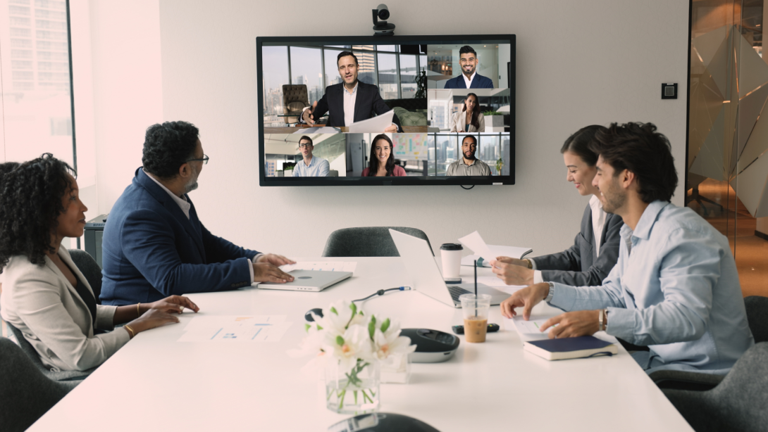 Diverse international business team discussing teamwork, work strategy, planning deal, partnership on online hybrid video conference, meeting at table and large screen, talking
