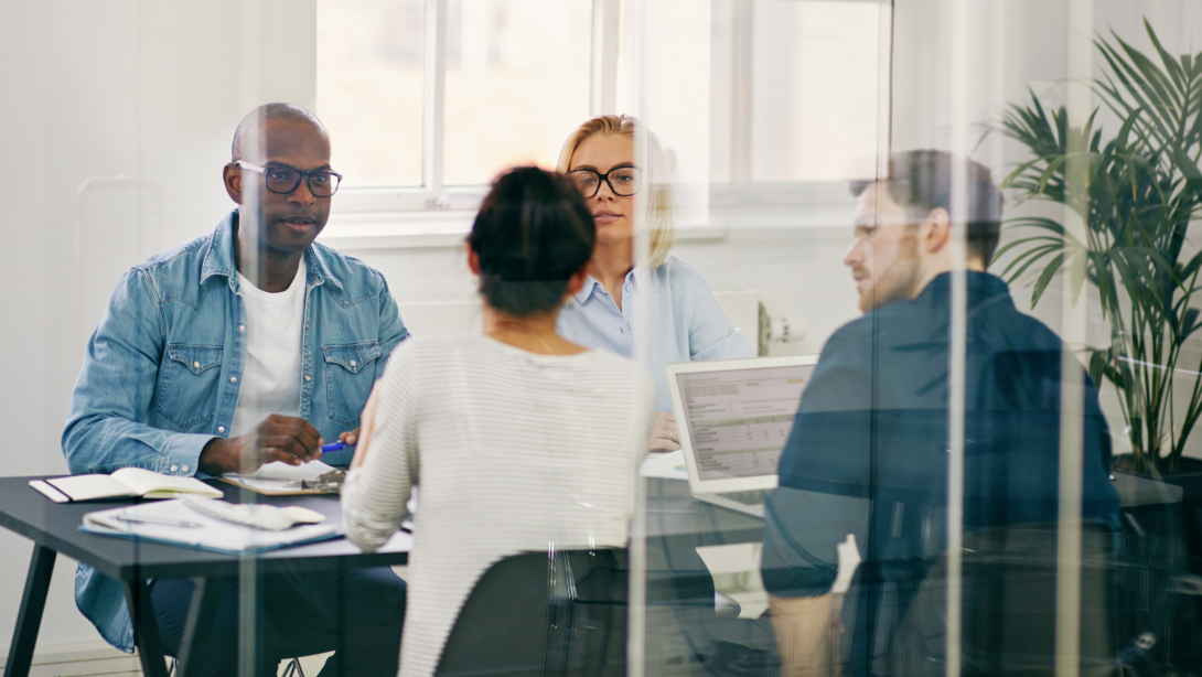 Diverse businesspeople meeting together inside of a glass walled