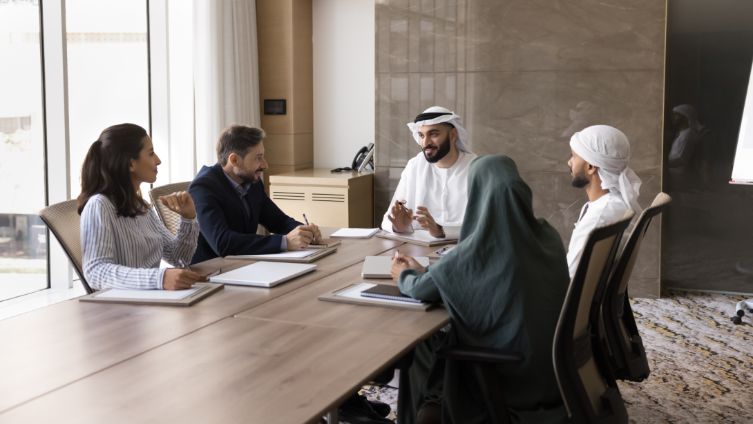 Happy young Arab business leader man talking to diverse partners at meeting. Multiethnic business team of Arabic and European colleagues discussing cooperation, teamwork.