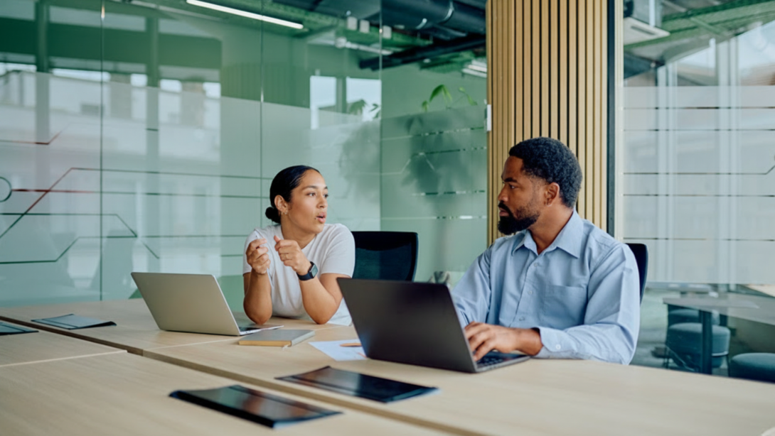 Two diverse business colleagues discussing ideas at an office table. They are collaborating and working together on a project 
