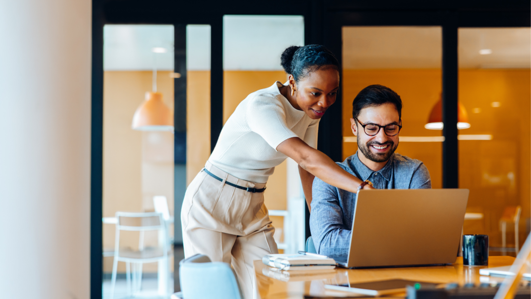 Business professionals discussing a project while using a laptop in an office