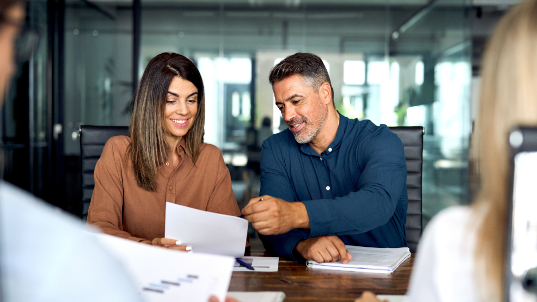 Professional executives business group working with documents at meeting in office. Smiling corporate board team having discussion planning company project strategy sitting at board room table.