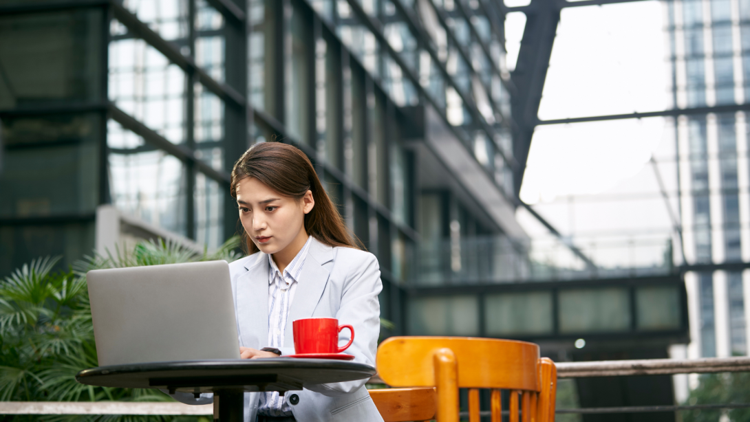 young asian professional business woman using laptop in outdoor coffee shop or sidewalk cafe