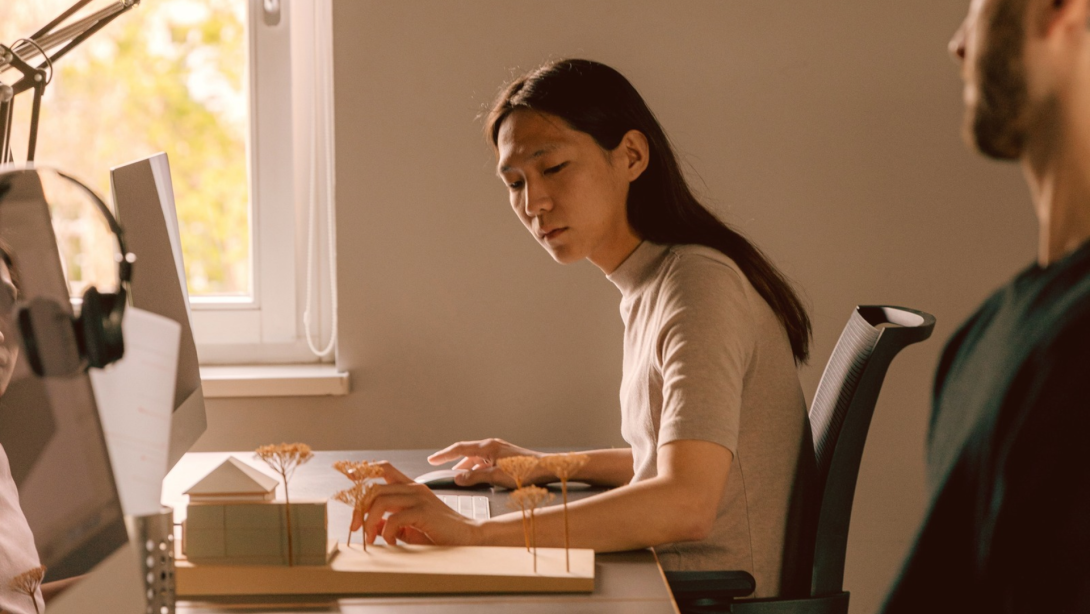 Asian woman working on a laptop, reviewing documents. 