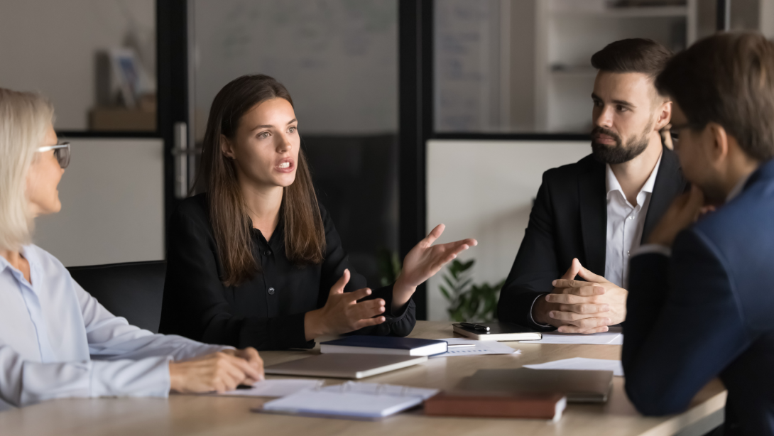 Serious young and mature colleagues brainstorm at conference table, listening speech of female team leader discuss project details, share ideas, consider cooperation, negotiate in office at briefing. 